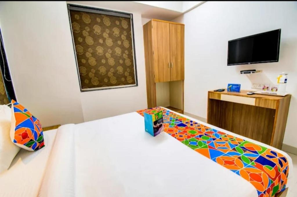 Un dormitorio con una cama blanca con un colorido cabecero estampado en ESTA EXPRESS,VIMAN NAGAR, en Pune