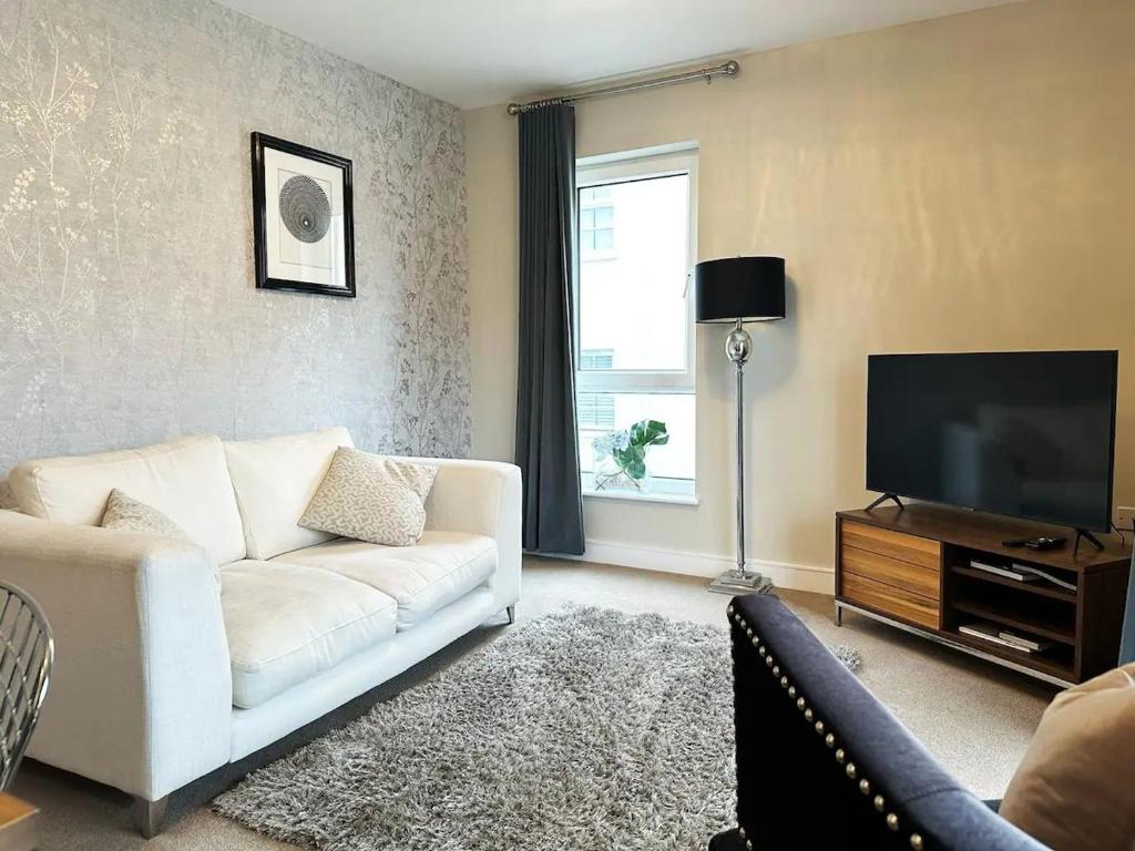 a living room with a white couch and a flat screen tv at Pass the Keys The Coliseum central modern apartment with balcony in Cheltenham