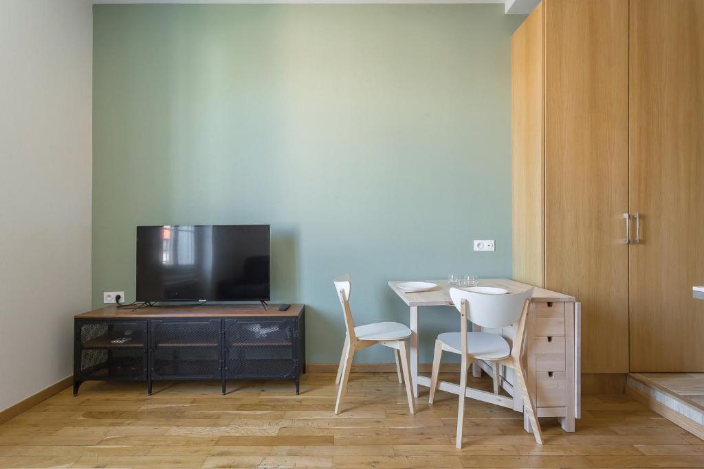 a room with a table and two chairs and a tv at Hamac Suites - Monplaisir fully equipped studio-2p in Lyon