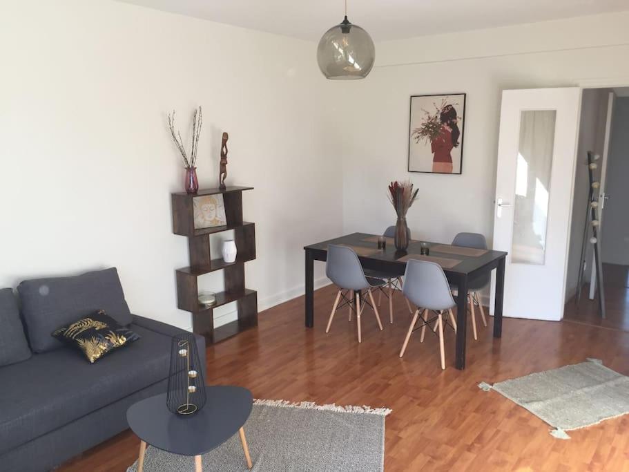 Una sala de estar con un sofá, una mesa y sillas. en Cosy large appartement 20 minutes downtown Paris, en Villejuif