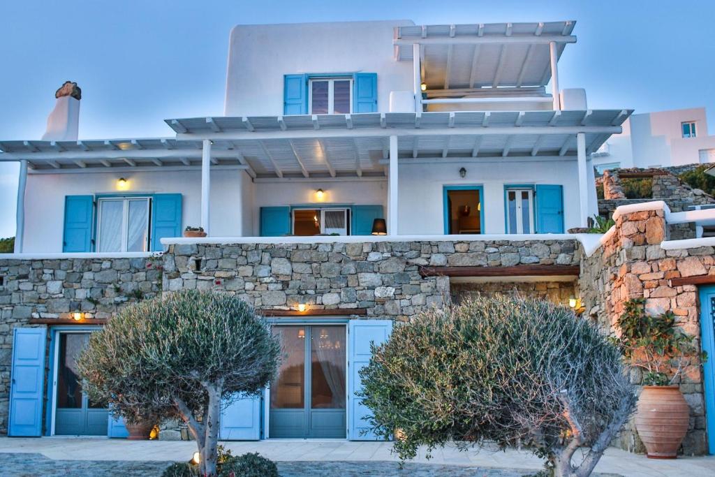 a house with blue doors and a stone wall at Exquisite Mykonos Villa - Villa Lakima - 6 Bedroom - Infinity Pool - Panoramic Sea And Sunset View - Pool Bar in Fanari