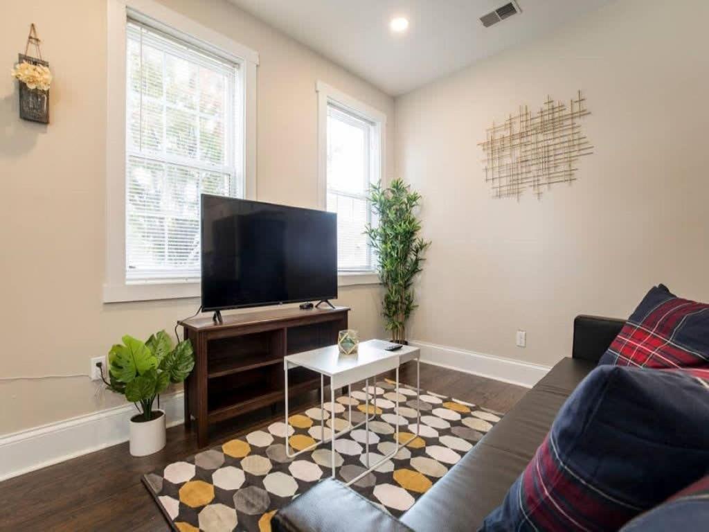uma sala de estar com um sofá e uma televisão de ecrã plano em Spacious 3BR House with Backyard in NULU CozySuites em Louisville