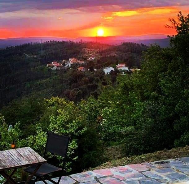 a bench sitting on top of a hill with a sunset at Bela Vista Alqueve - 2 houses with pool, 2 casas com piscina in Arganil