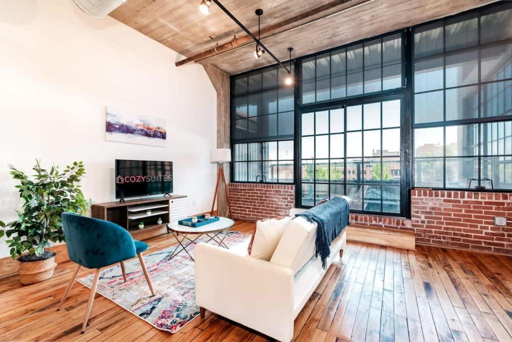 a living room with a brick wall and a white couch at Stunning 1BR Adler Loft by CozySuites in Saint Louis