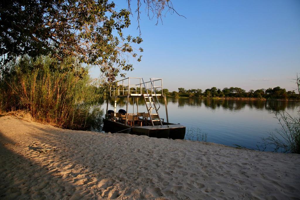 un barco sentado en el agua junto a una playa en Zambezi Dusk, en Livingstone