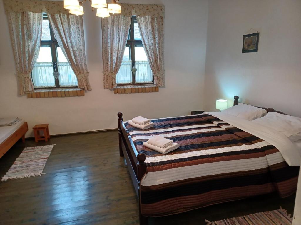 a bedroom with a large bed with three windows at Erdut kuća za odmor in Erdut