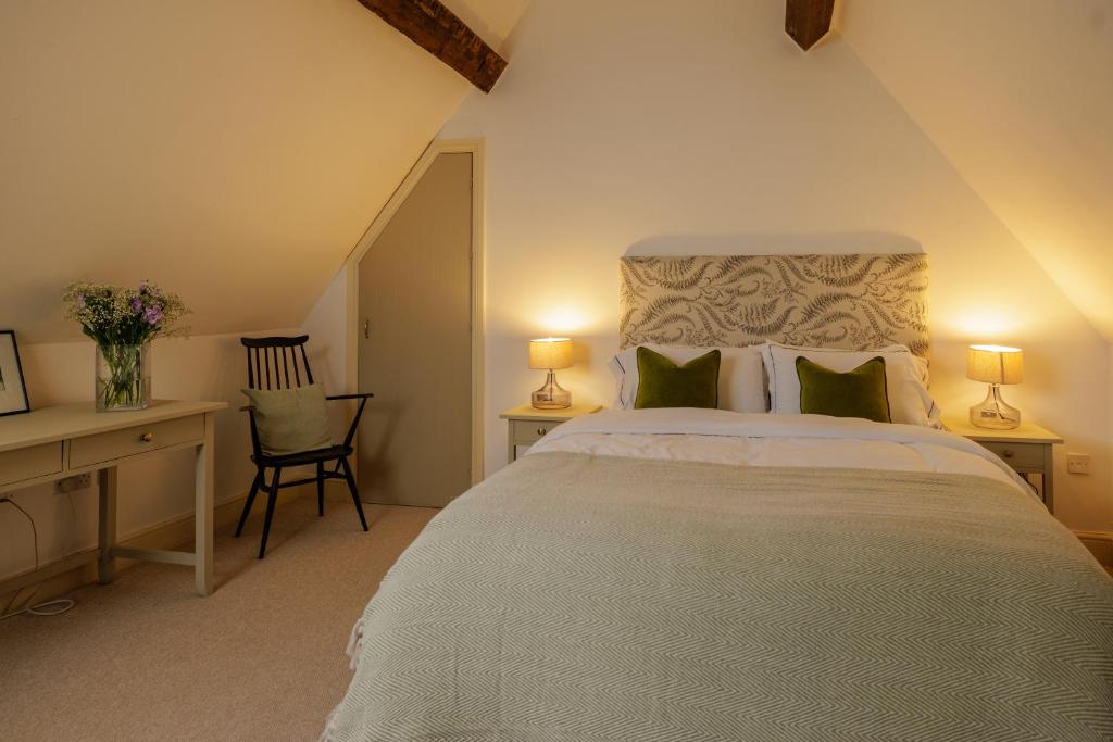 a bedroom with a bed and a desk with two lamps at The Dashwood in Kirtlington