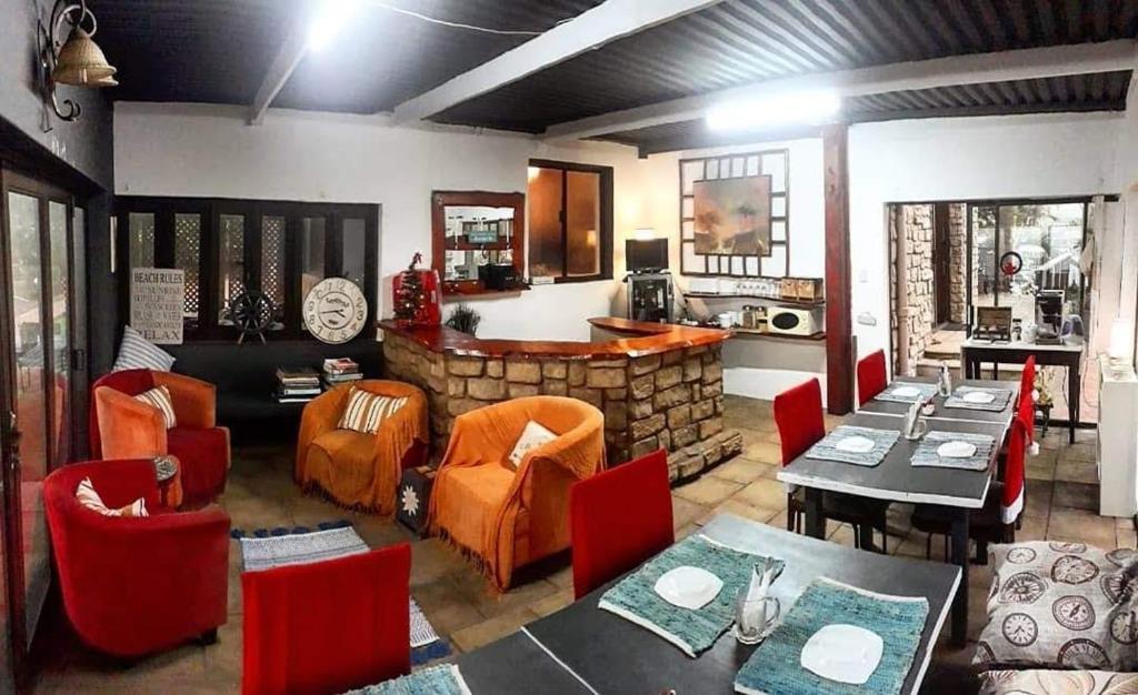 a restaurant with tables and chairs and a stone bar at Bayview Guest House in Amanzimtoti
