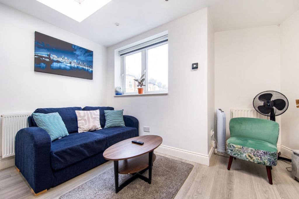 Cosy 1 Bed apartment with FREE PARKING close to Underground station zone 2 for quick access to Central London up to 5 guests في لندن: غرفة معيشة مع أريكة زرقاء وكرسي
