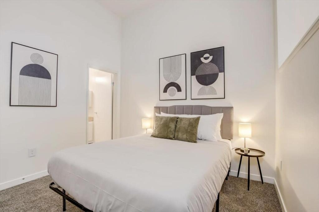 a white bedroom with a large bed and two lamps at CozySuites - 1BR with Direct Skybridge Access #2 in Indianapolis