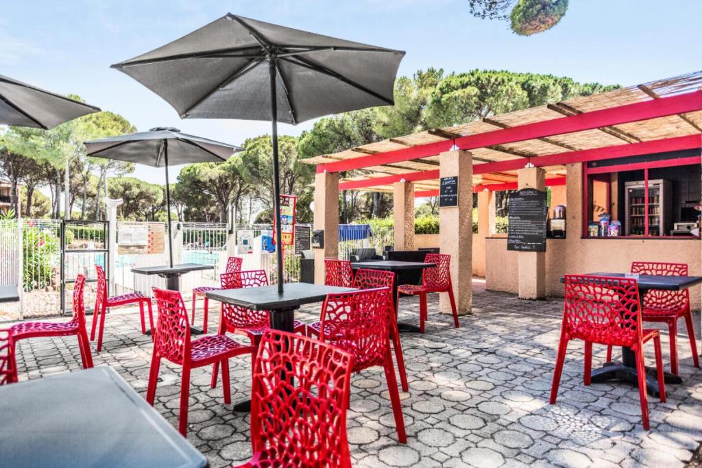 a patio with red chairs and tables and umbrellas at Résidence Saint-Raphaël Valescure - maeva Home - Studio 2 personnes - Séle 41 in Valescure