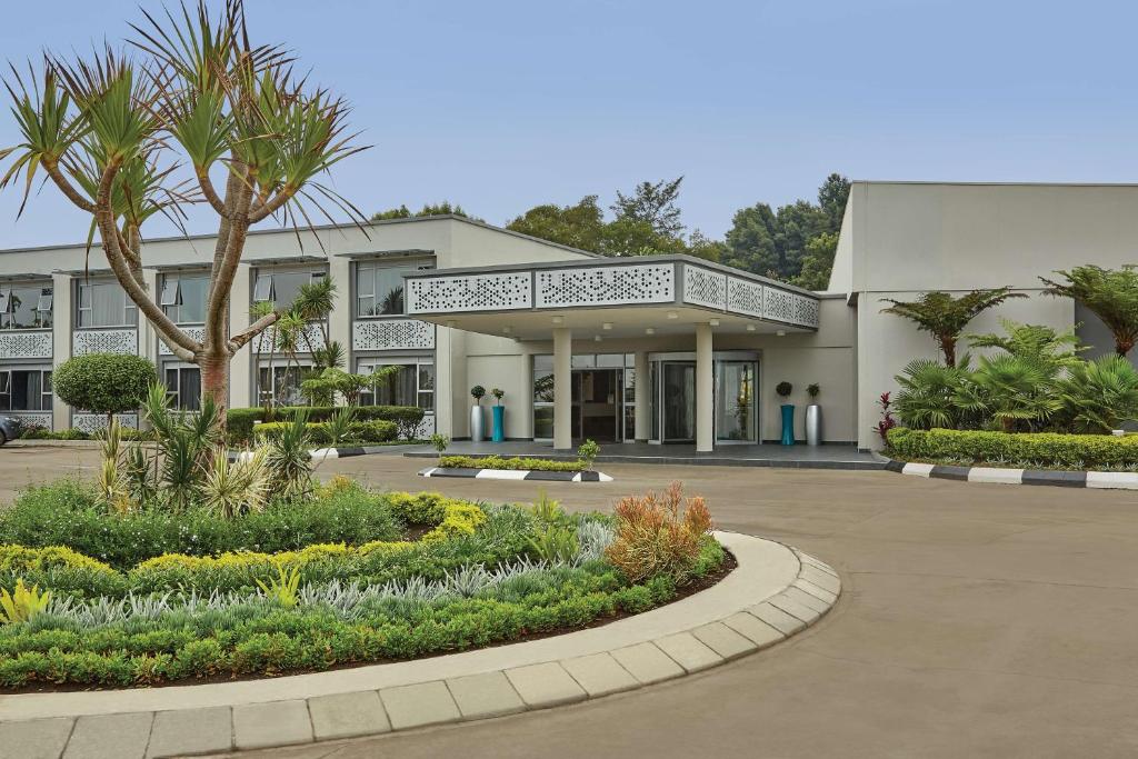 duży biały budynek z palmą przed nim w obiekcie Garden Court Mthatha w mieście Mthatha