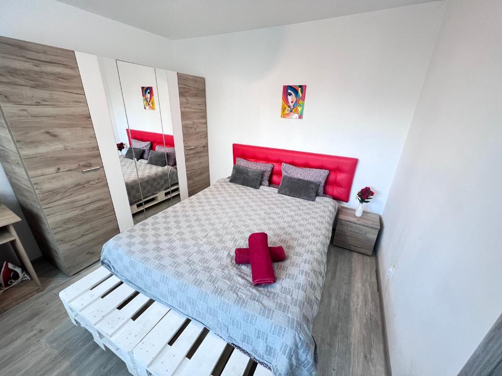 a bedroom with a bed with a red cross on it at 3 rooms apartment Airy & Bright Palas Style in Iaşi