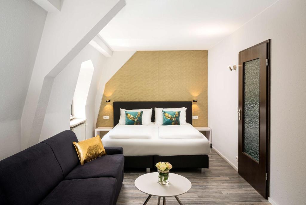 a hotel room with a bed and a couch at Arthotel ANA Gold in Augsburg