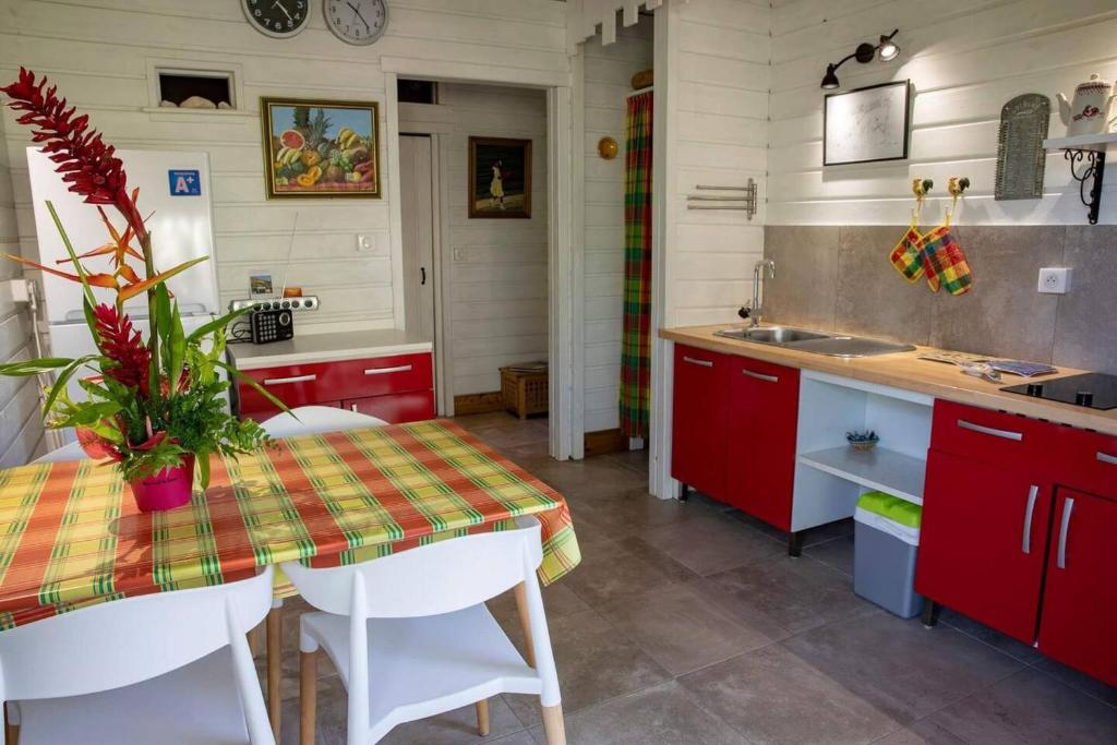 een keuken met rode kasten en een tafel en een wastafel bij Chalet de 2 chambres a Vieux Habitants a 300 m de la plage avec terrasse et wifi in Vieux-Habitants
