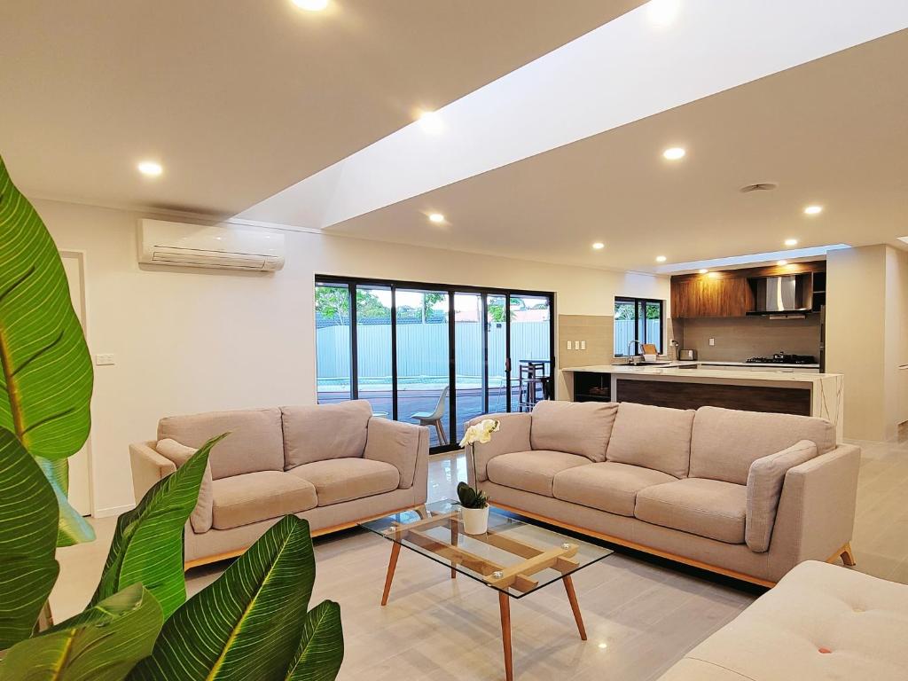 a living room with two couches and a table at Bay Villa with 5 Bedrooms and 5 Bathrooms in Whangaparaoa