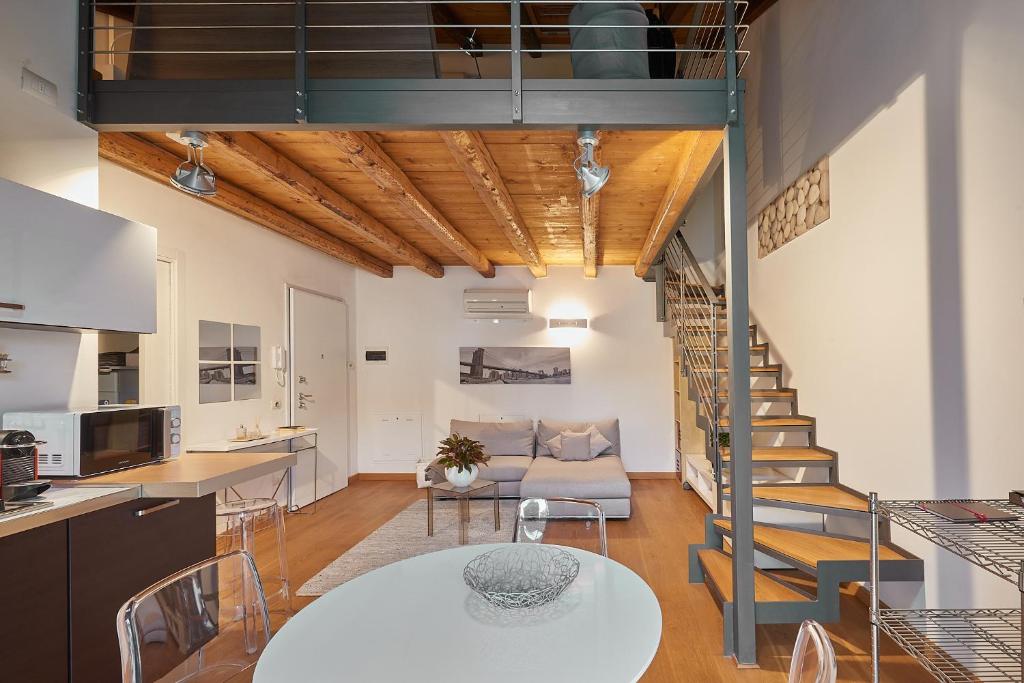 uma cozinha e sala de estar com uma escada num loft em Casa Cozy - La Guarida em Pradamano
