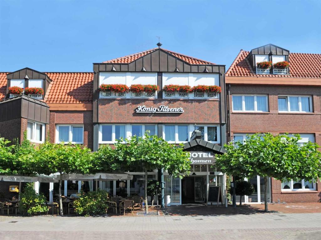 ein großes Gebäude mit Tischen und Stühlen davor in der Unterkunft Hotel-Restaurant Thomsen in Delmenhorst