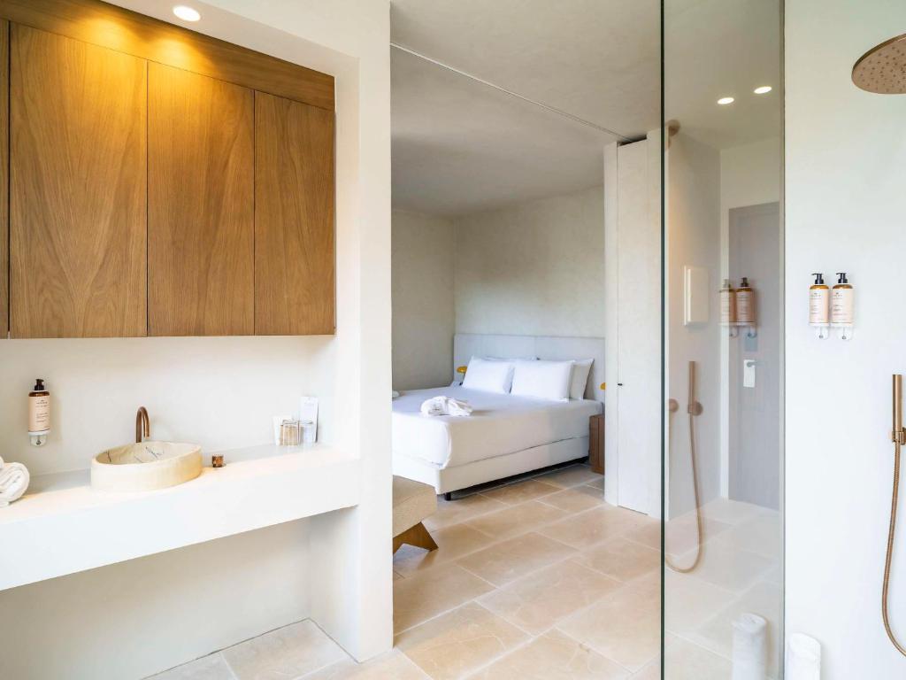 a bathroom with a bed and a glass shower at Mercure Benidorm in Benidorm