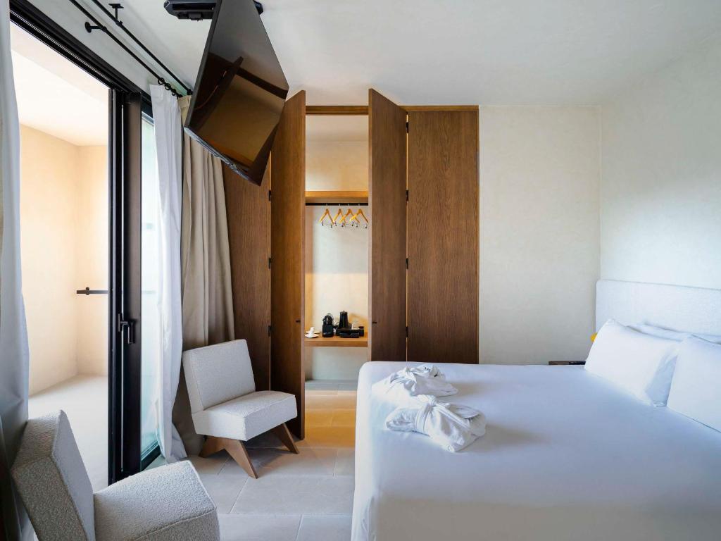 a hotel room with a white bed and a tv at Mercure Benidorm in Benidorm