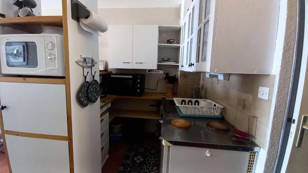 a small kitchen with white cabinets and a refrigerator at Résidence Pointe Vermeille - 2 Pièces pour 6 Personnes 984 in Le Barcarès