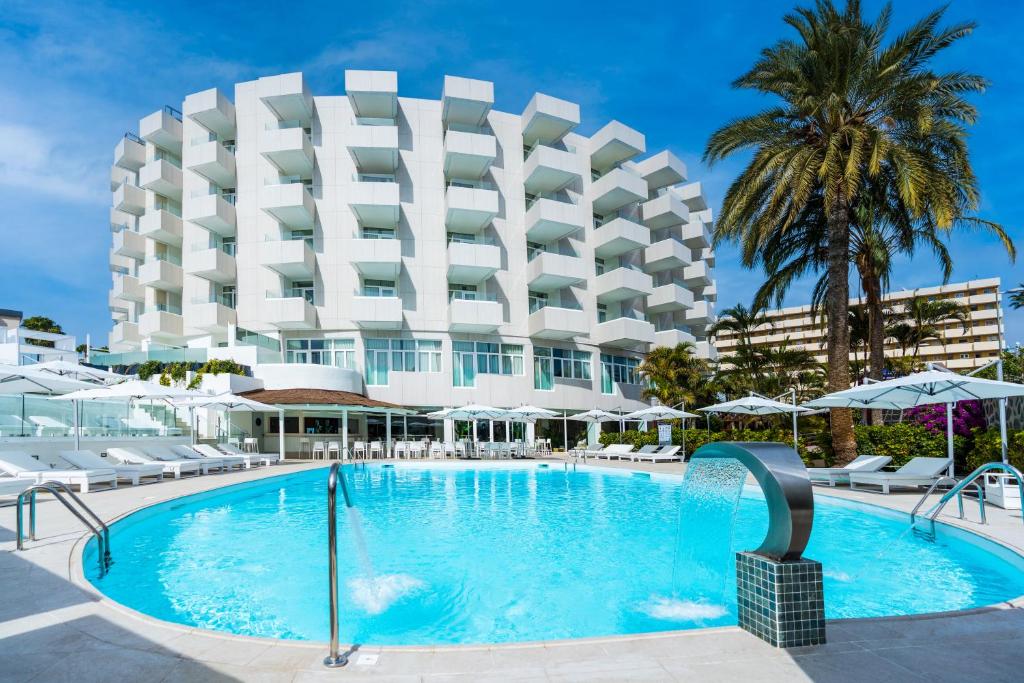 un hotel con piscina frente a un edificio en HL Rondo Hotel, en Playa del Inglés