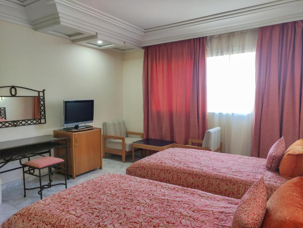 a hotel room with two beds and a television at Hotel Idou Tiznit in Tiznit