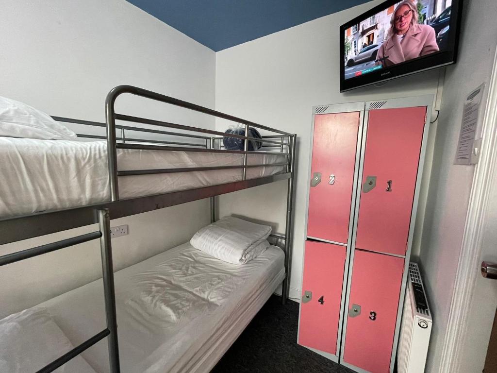 a room with two bunk beds and a flat screen tv at Backpackers Blackpool - Family Friendly Hotel in Blackpool