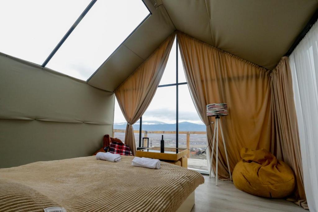 a bedroom with a large bed with a large window at პანორამა სხალტბა in Mtskheta