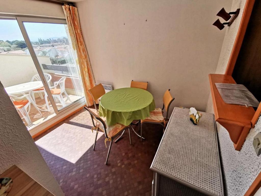 a room with a green table and chairs and a window at RESIDENCE DE LA PLAGE - Studio pour 4 Personnes 94 in Port Leucate
