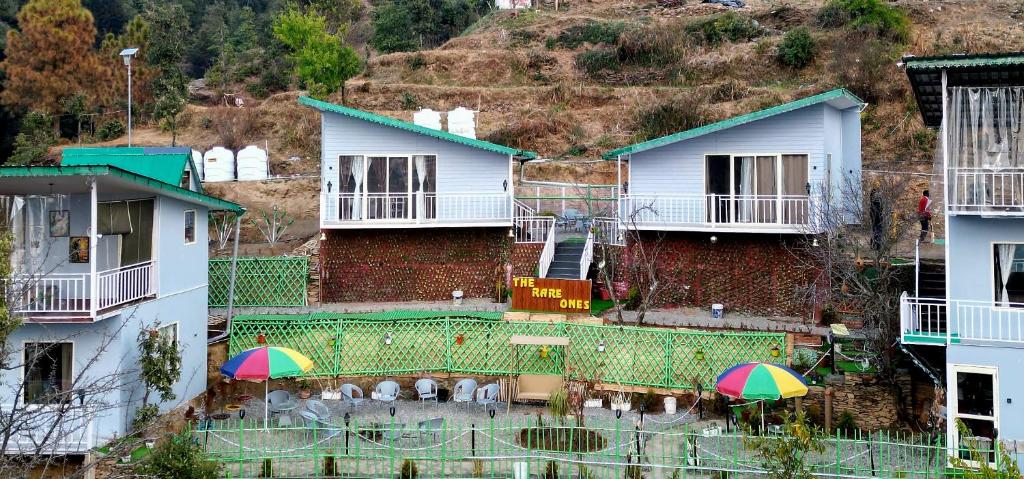 a group of buildings with umbrellas in front of them at The Rare Ones - Resorts, Cafe & Game Zone in Mukteshwar