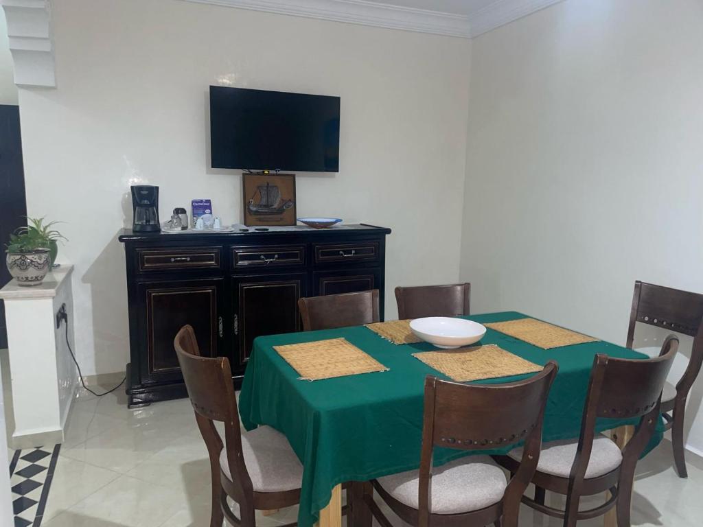 una sala da pranzo con tavolo verde e TV di Dar Malaika a Oualidia