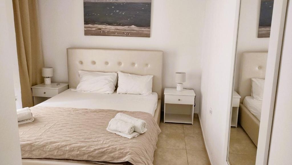 een witte slaapkamer met een bed en twee nachtkastjes bij Lion Apartment in Limenas