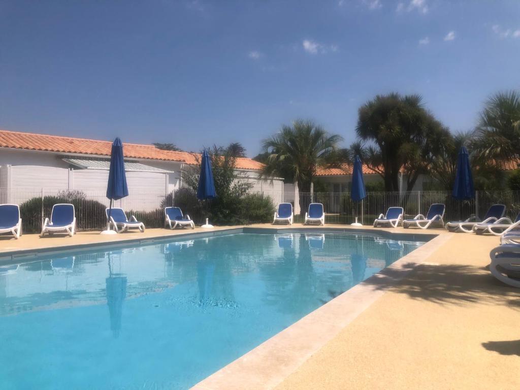 una gran piscina con sillas y sombrillas en Le Petit Bois, en Sainte-Marie-de-Ré