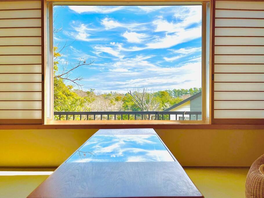 - une fenêtre avec un tapis en face de celle-ci et une vue dans l'établissement Cozy Villa with Hot springs and Nature, à Itō
