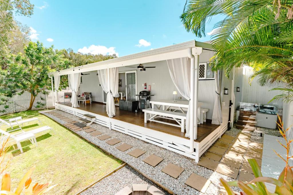 a white house with a porch and a patio at Private Outdoor Spa, Fire Pit, Cinema Room - THE COTTAGE COOLUM BEACH in Coolum Beach