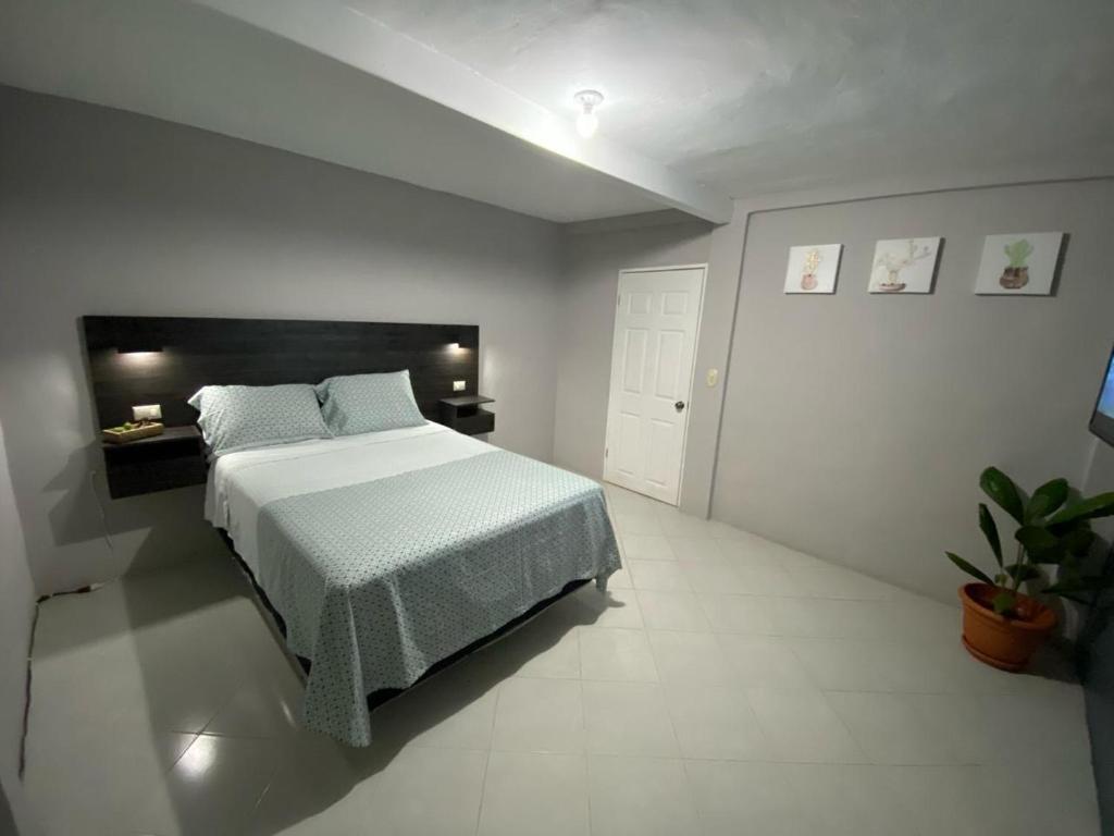 a bedroom with a large bed in a white room at Habitación cerca del aeropuerto #1 