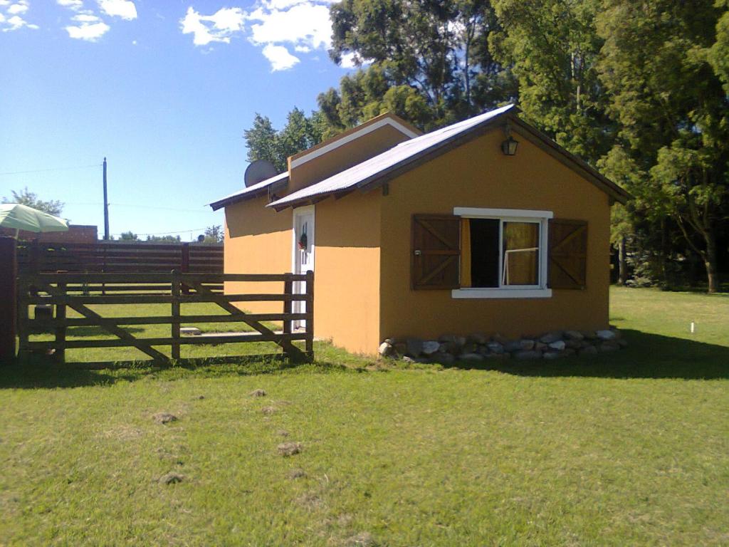 una pequeña casa en un campo con una valla en La Nilda en Tandil