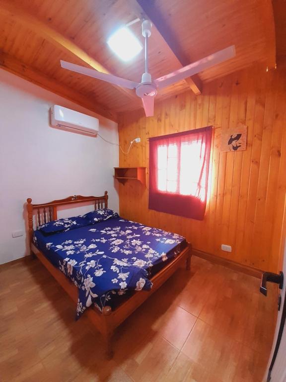 1 dormitorio con 1 cama en una habitación de madera en Cabañas Ema Luz & La Soñada en Gobernador Roca