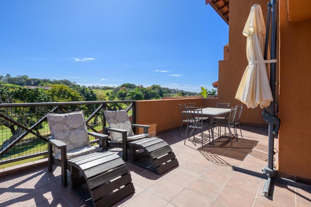 サウスブルームにあるSan Lameer Villa 10412 - 1 Bedroom Classic - 2 pax - San Lameer Rental Agencyのテーブルと椅子と傘のあるバルコニー