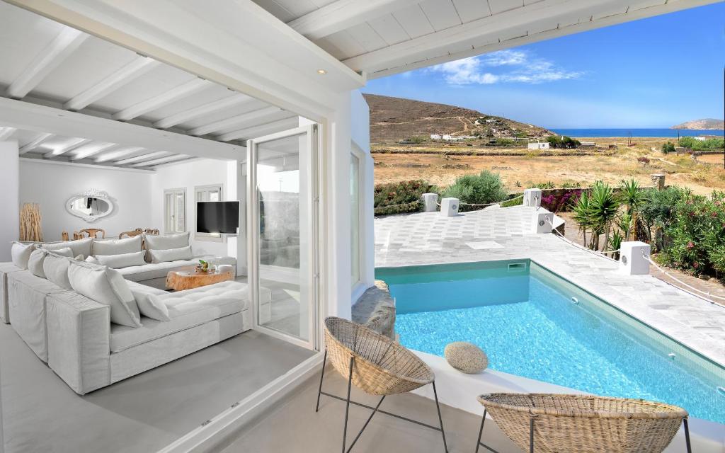 a living room with a couch and a swimming pool at Mykonos Dream Villas in Ftelia