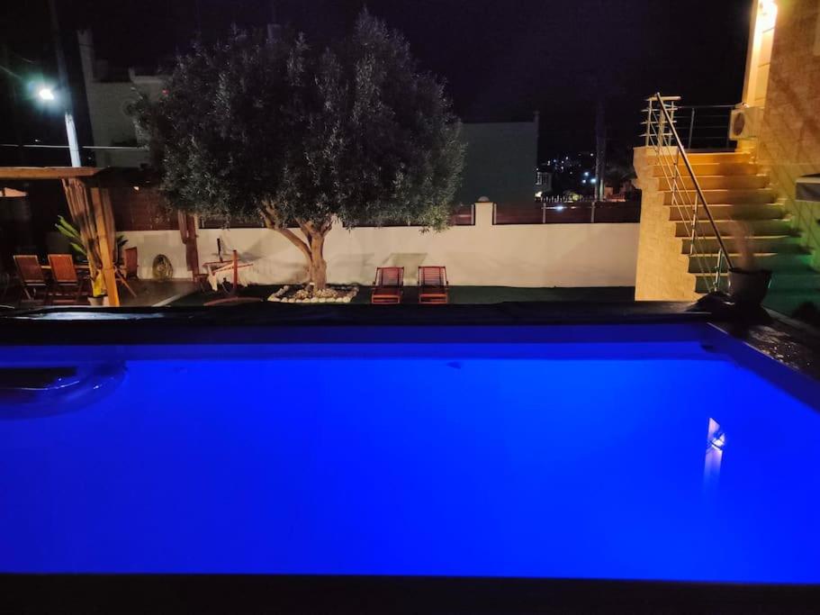 - une piscine bleue la nuit avec un arbre dans l'établissement Rsquared (Riviera Residence), à Aghia Marina
