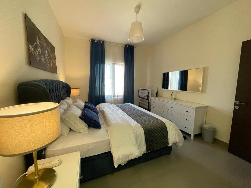 Apartment F14 - Samarah Resort في السويمة: غرفة نوم بسرير وخزانة وتلفزيون