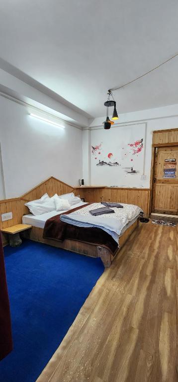 - une chambre avec un grand lit et un tapis bleu dans l'établissement PineRoots Homestay & Cafe, à Jibhi
