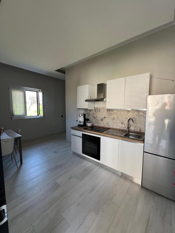 eine Küche mit weißen Schränken, einer Spüle und einem Kühlschrank in der Unterkunft Brass apartment in Castellammare di Stabia