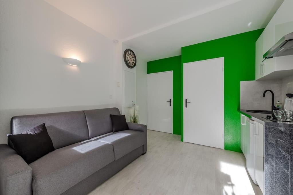 - un salon avec un canapé et un mur vert dans l'établissement La Place de Toscane 1, à Serris