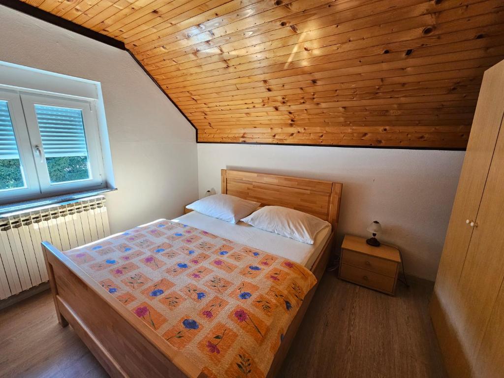 a bedroom with a bed and a wooden ceiling at House Mirjana in Smoljanac