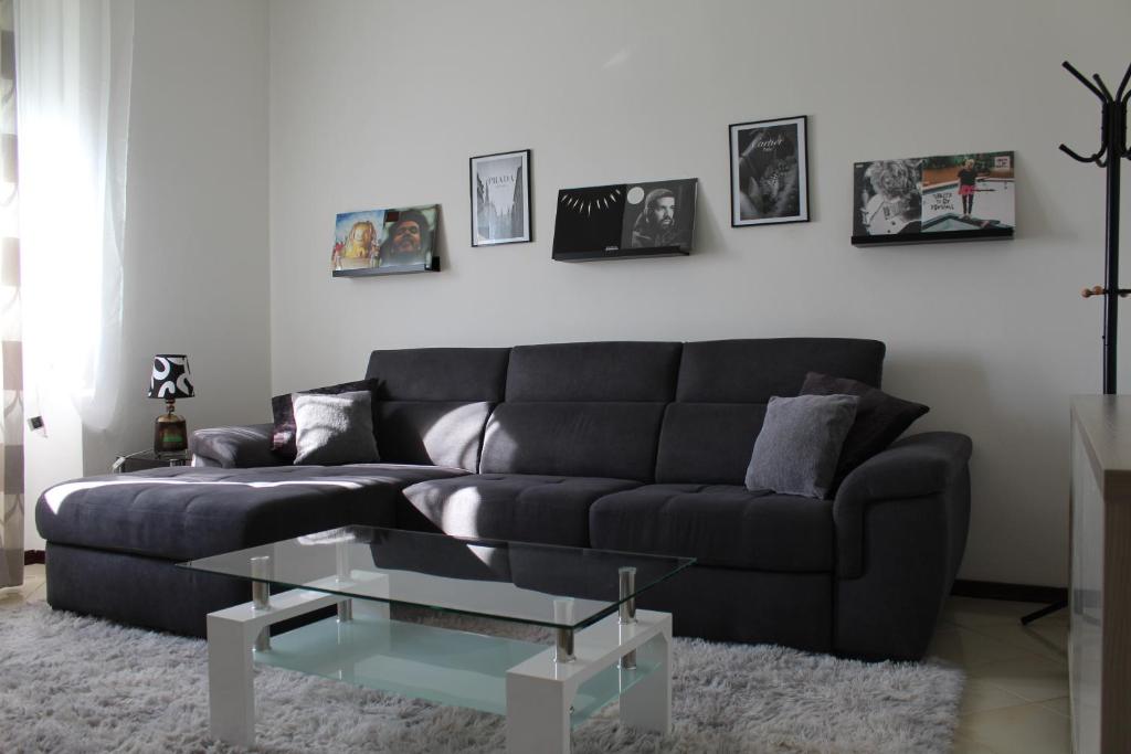 a living room with a black couch and a glass coffee table at Appartamento del Sol, Free private parking, Free Wi-Fi in Varese