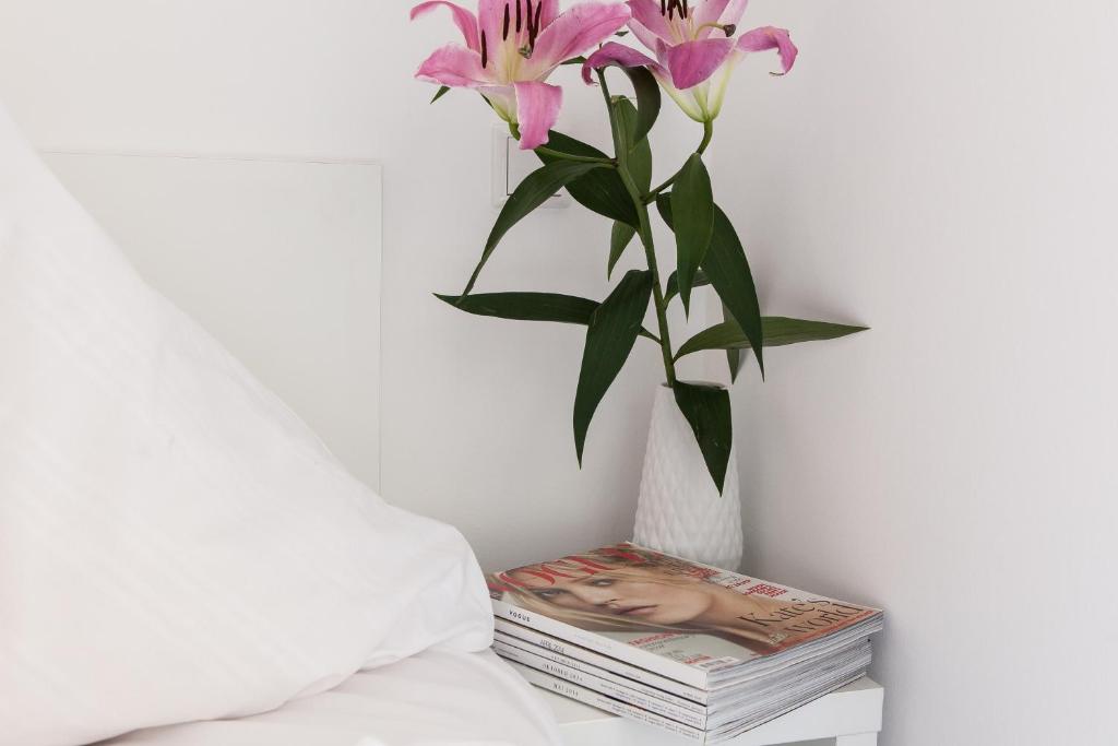 eine Vase mit rosa Blumen auf einem Stapel von Zeitschriften in der Unterkunft BNB near Brandenburg Gate - Rooms & Apartments in Berlin