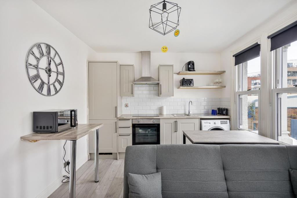 a kitchen with a couch and a clock on the wall at Stylish 2-Bedroom Flat in Walthamstow in London